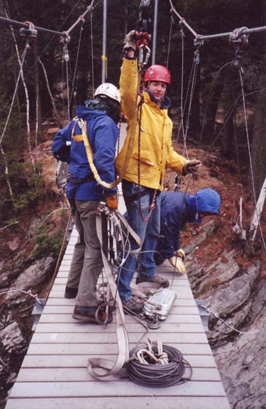 men tightening cables on suspension bridge